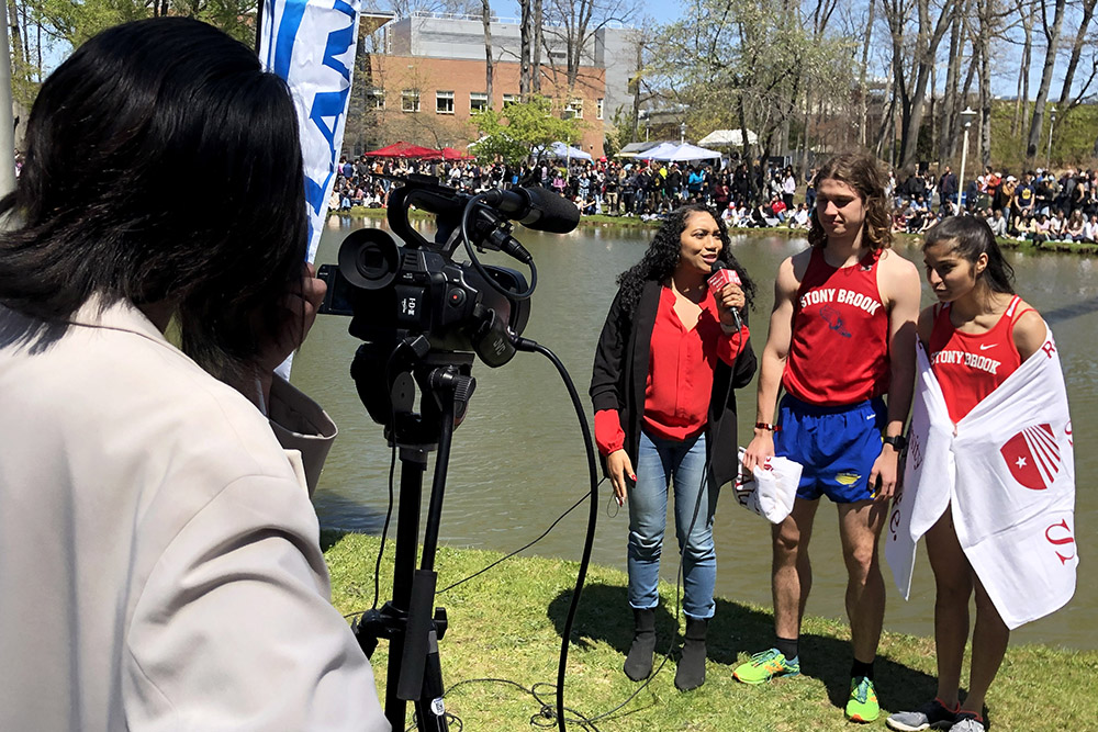 Student reporter interviewing two Roth Regatta participants along the pond shore