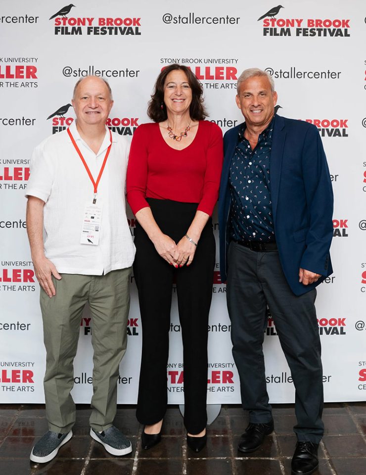 President Andrea Goldsmith with her husband, Arturo Salz (left), and SBFF Director Alan Inkles standing in front of a Stony Brook Film Festival backdrop.