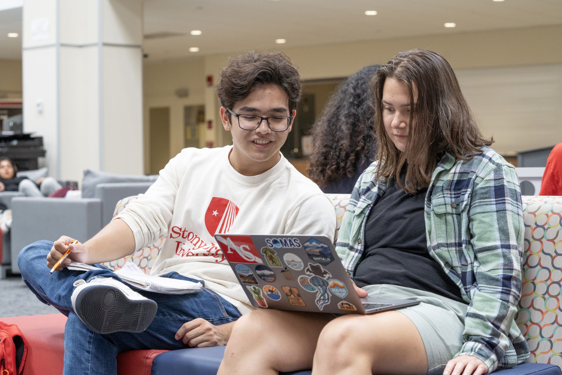Two Stony Brook students on their laptop looking up information about Giving Day