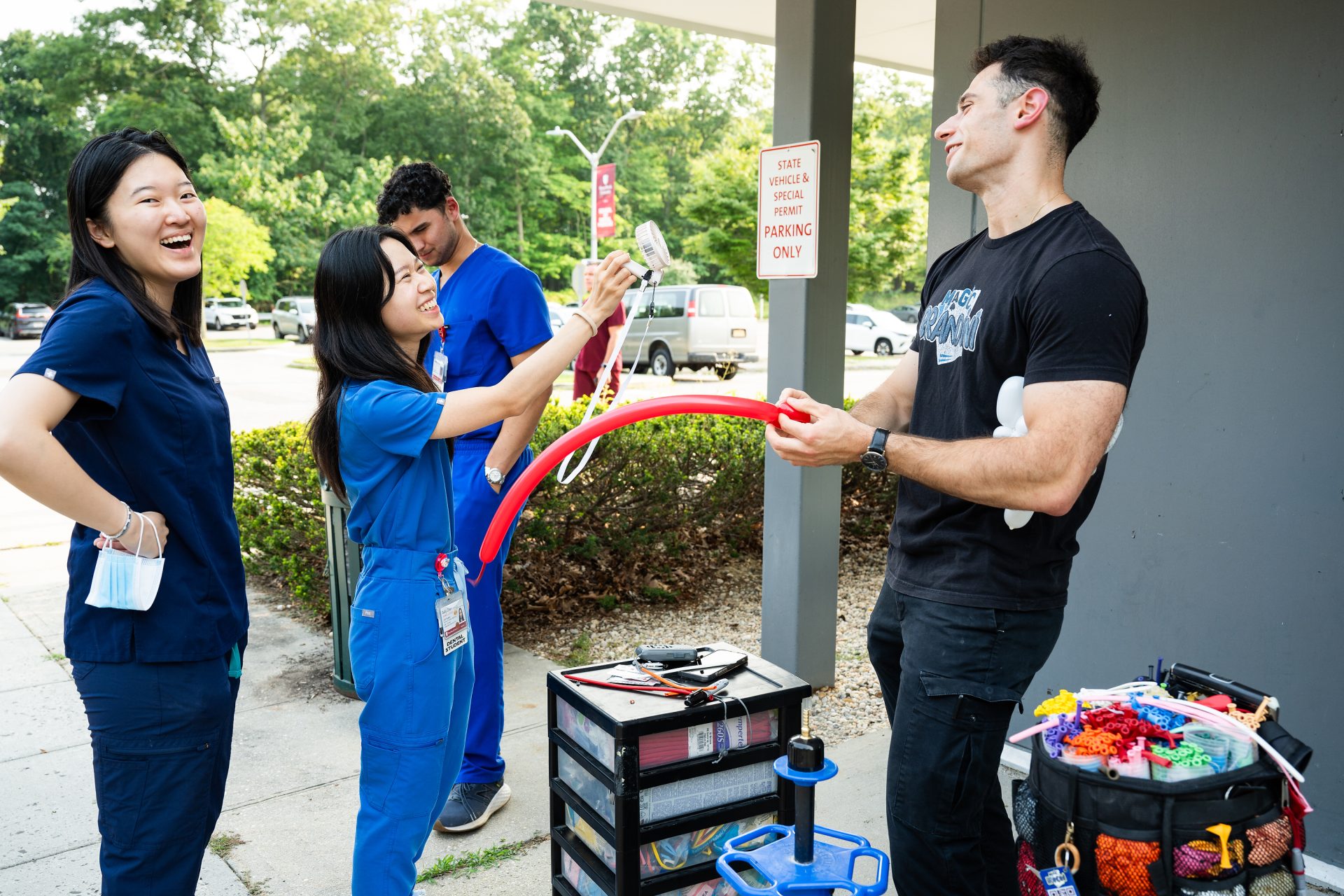 Axelrod creates balloon art for a fellow dental student. He is wearing his "Magic Brandini" tee shirt.