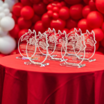 Awards for Stony Brook Athletics Hall of Fame sit on a round table with a red table cloth. Red and white balloon wall in the background.