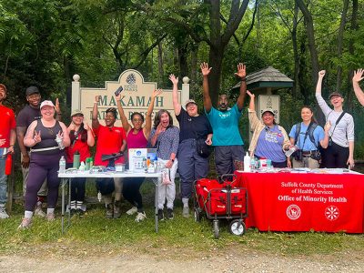 A group of people with their hands raised at tables in a park