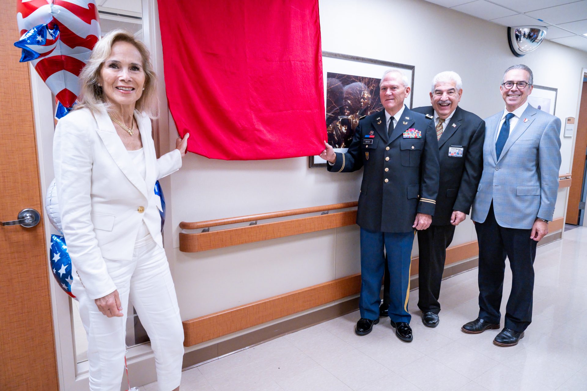 Carolyn Sanchez Woycik and Col. E. David Woycik Jr. (Ret.), Esq. holding a red curtain to unveil a plaque