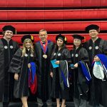 Zahraa Krayem Stuart surrounded by fellow graduaes and her professor